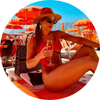 Woman sitting on a beach chair with a colorful umbrella, wearing a red swimsuit and straw hat.